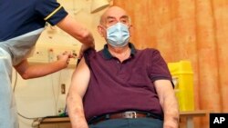 82-year-old Brian Pinker receives the Oxford University/AstraZeneca COVID-19 vaccine from nurse Sam Foster at the Churchill Hospital in Oxford, England, Monday, Jan. 4, 2021.