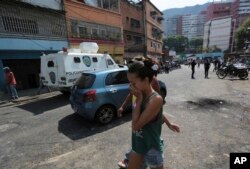 A resident covers her month from tear gas fired by Bolivarian National Police outside of a grocery and liquor store to disperse looters during a protest in Caracas, Venezuela, April 12, 2017.