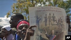 A man holds a calendar depicting Haiti's ousted President Jean-Bertrand Aristide during a protest in Port-au-Prince, Haiti, February 18, 2011