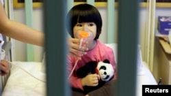 Một bé gái hai tuổi được cho đeo máy xông mũi họng tại Bệnh viện Thiếu nhi Quốc tế Thế kỷ Mới sau khi thủ đô Bắc Kinh ban hành "báo động đỏ" lần hai về ô nhiễm không khí, ngày 22/12/2015.