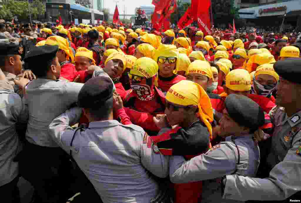 Workers push police officers to brake the barricade during a Mayday rally at business district in Jakarta, Indonesia, May 1, 2018.