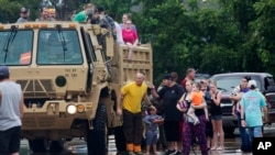 Members of the Louisiana Army National Guard unload people at a rally point after they were rescued from rising floodwater near Walker, La., after heavy rains inundated the region, Sunday, Aug. 14, 2016.