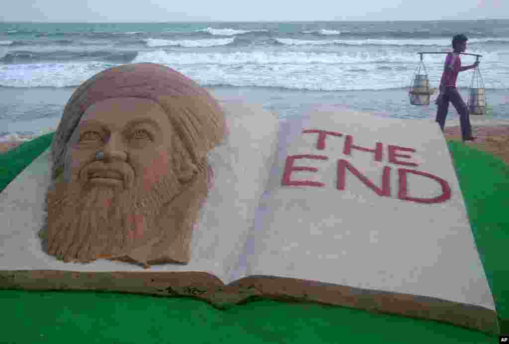 A vendor walks past a sand sculpture of al-Qaida leader Osama bin Laden created by Indian sand artist Sudarshan Patnaik on a beach in Puri in eastern Indian state of Orissa, May 2, 2011 (Reuters)