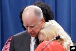 California Gov. Jerry Brown is hugged by Holly Dias, a Burger King employee who praised Brown's announcement of proposed legislation to increase the state's minimum wage to $15 per hour by 2022, March 28, 2016.