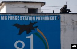 An Indian military commando is seen on the top of a building at the Indian air force base in Pathankot, India, Jan. 5, 2016, following a militant attack on the base.