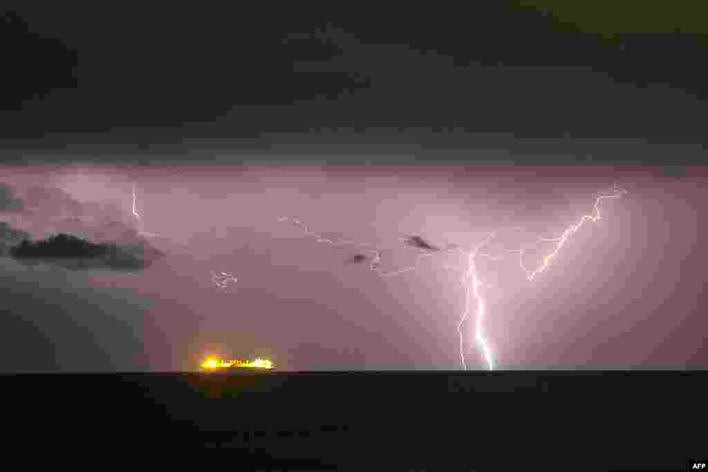 Sebuah kapal tampak di tengah laut Mediterania saat kilat menyambar, terlihat dari utara Tel Aviv, Israel.