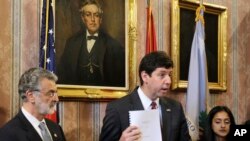 U.S. Attorney Steven Dettelbach, center, holds up the settlement agreement with the City of Cleveland a news conference, May 26, 2015, in Cleveland.