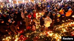 People hold candles at the memorial site of last year's truck attack in a Christmas market, which killed 12 people and injured many others, at Breitscheidplatz square in Berlin, Dec. 19, 2017. 