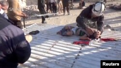A still image taken from a video posted to a social media website on April 4, 2017, shows a civil defense member helping a child who is being sprayed with water, said to be in the town of Khan Sheikhoun.