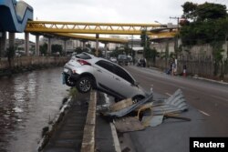 A car is nearly pushed into a channel after heavy rains in Vila Prudente neighborhood in Sao Paulo, Brazil, March 11, 2019.
