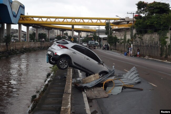 A car is nearly pushed into a channel after heavy rains in Vila Prudente neighborhood in Sao Paulo, Brazil, March 11, 2019.