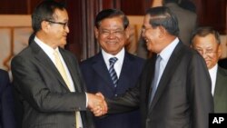 Cambodian Prime Minister Hun Sen, second from right, shakes hands with the main opposition party leader Sam Rainsy, left, of Cambodia National Rescue Party, as Deputy Prime Minister Sar Kheng, second from left, looks on after a meeting in Senate headquart