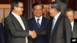 Cambodian Prime Minister Hun Sen, second from right, shakes hands with the main opposition party leader Sam Rainsy, left, of Cambodia National Rescue Party, as Deputy Prime Minister Sar Kheng, second from left, looks on after a meeting in Senate headquarter, file photo. 