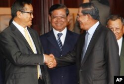 Cambodian Prime Minister Hun Sen, second from right, shakes hands with the main opposition party leader Sam Rainsy, left, of Cambodia National Rescue Party, as Deputy Prime Minister Sar Kheng, second from left, looks on after a meeting in Senate headquart