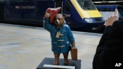 Tourists take photographs on their tablets and smart phone of a statue of 'Paddington Bear' on the platform at Paddington railway station in London.