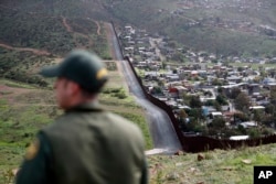 Border Patrol agent Vincent Pirro looks on near a border wall that separates the cities of Tijuana, Mexico, and San Diego, Feb. 5, 2019, in San Diego.