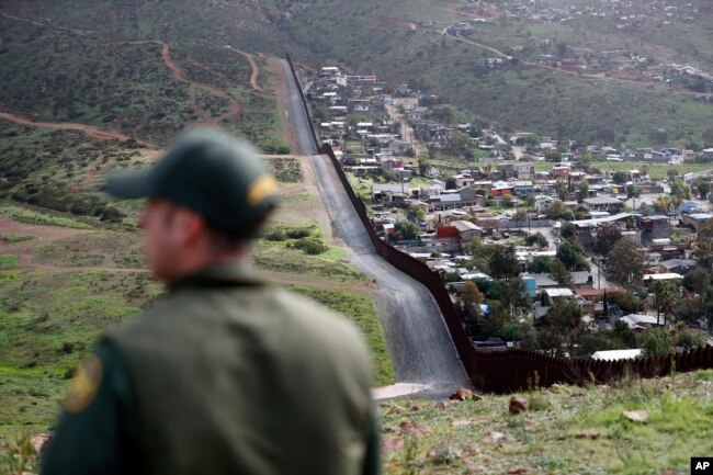 Border Patrol agent Vincent Pirro looks at a border wall that separates the cities of Tijuana, Mexico, and San Diego, Feb. 5, 2019, in San Diego.