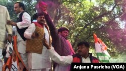 Waving party flags, party workers throw color in a mark of celebration as Rahul Gandhi became Congress Party president. 