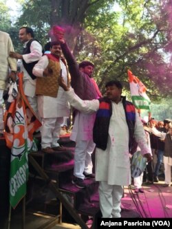 Waving party flags, party workers throw color in a mark of celebration as Rahul Gandhi became Congress Party president.