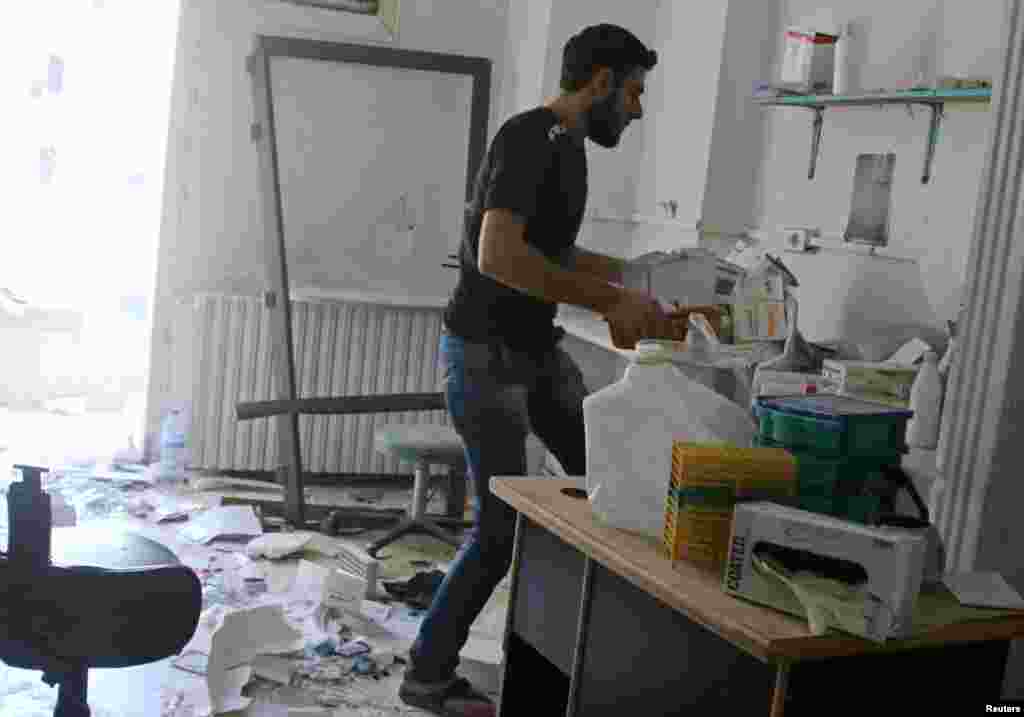 Seorang pria memindahkan obat-obatan di dalam rumah sakit al-Quds yang hancur terkena serangan udara di Aleppo (28/4). (Reuters/Abdalrhman Ismail)