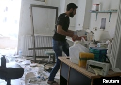 A man removes medicine inside al-Quds hospital after it was hit by airstrikes, in a rebel-held area of Syria's Aleppo, April 28, 2016.