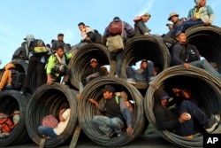 Central American migrants, part of the caravan hoping to reach the U.S. border, get a ride on a truck carrying rolls of steel rebar, in Irapuato, Mexico, Nov. 12, 2018.