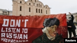 FILE - An activist holds a banner with a portrait of Dutch artist Vincent van Gogh as he demonstrates outside the Dutch embassy in Kyiv, Ukraine, Feb. 5, 2016. The activists demanded that Dutch people ignore what they say are Russian propaganda, ahead of an upcoming Dutch Ukraine-European Union Association Agreement.