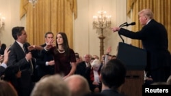 FILE - A White House staff member reaches for the microphone held by CNN's Jim Acosta as he questions President Donald Trump.