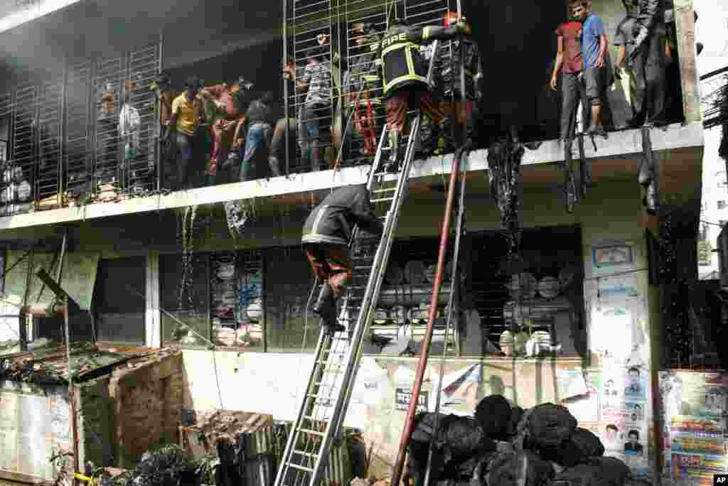 Bangladeshi firefighters and workers try to douse the fire at a garment-factory in Dhaka, Bangladesh, after a similar incident killed more than 100 people on the outskirts of the city, November 26, 2012.