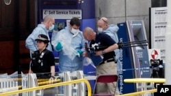 Forensic officers investigate the scene near the Manchester Arena, Manchester, England, May 23, 2017, the day after the suicide attack at an Ariana Grande concert that left 22 people dead as it ended on Monday night.