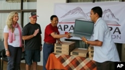 In this May 9, 2019, photo, Apa Sherpa, center, hands over a computer to Chakra Karki, representative of a school from Dhuske, Okhaldhunga district in Kathmandu, Nepal.