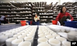 FILE - Workers coat potteries with enamel in a factory in Bat Trang village, Hanoi, Vietnam. Foreign and local businesses hope Vietnam’s ruling Communist Party will modernize an economy dominated by state companies.