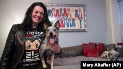 In this Thursday, January 31, 2019, photo Lisa Topol poses for a photo with her two rescue dogs, Schmutzy, right, and Plop, in New York. Topol recently had the DNA tested for both dogs.