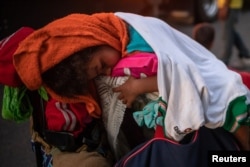 A young migrant, traveling with a caravan of thousands from Central America en route to the United States, sleeps atop baggage resting on a stroller while looking to go to Arriaga from Pijijiapan, Mexico, Oct. 26, 2018.