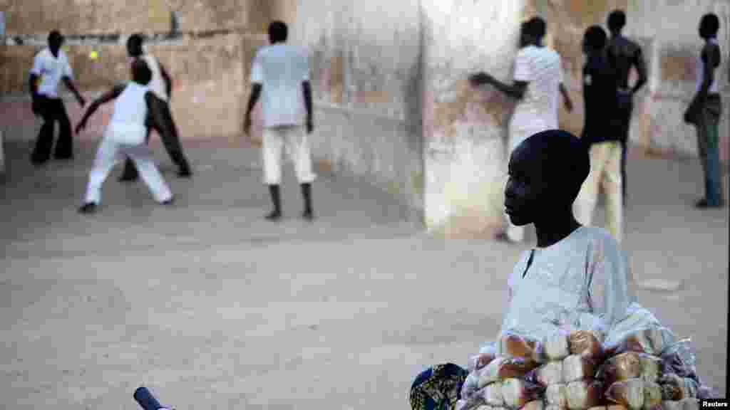 A boy sells bread near a court where youths play Eton fives game in a court in Katsina.