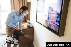 In this Monday, July 6, 2020 photograph, an employee wearing a mask due to the coronavirus pandemic fogs disinfectant in a hotel room at the Rove City Centre Hotel in Dubai, United Arab Emirates. Dubai reopened for tourists Tuesday, July 7, 2020.