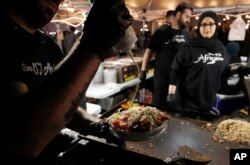 Ali el Romh dari Peepo's Subs and Shawarma membuat sepiring ayam di Festival Sahur Ramadhan. (Foto: AP)