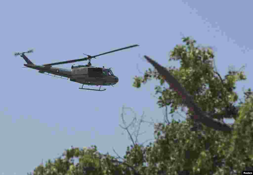 A military helicopter flies overhead as police officers and soldiers secure the area before the motorcade of Chinese Premier Li Keqiang passes through Islamabad.