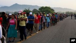 Migrants walk along the road after Mexico's federal police briefly blocked the highway in an attempt to stop a thousands-strong caravan of Central American migrants from advancing, outside the town of Arriaga, Mexico, Oct. 27, 2018.