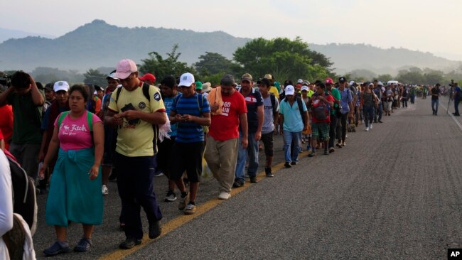 Migrants walk along the road after Mexico's federal police briefly blocked the highway in an attempt to stop a thousands-strong caravan of Central American migrants from advancing, outside the town of Arriaga, Mexico, Oct. 27, 2018.