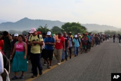 Migrants walk along the road after Mexico's federal police briefly blocked the highway in an attempt to stop a thousands-strong caravan of Central American migrants from advancing, outside the town of Arriaga, Mexico, Oct. 27, 2018.