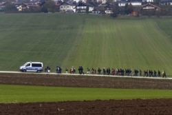 FILE - Immigrants are escorted by German police to a registration center, after crossing the Austrian-German border in Wegscheid near Passau, Germany, Oct. 20, 2015.