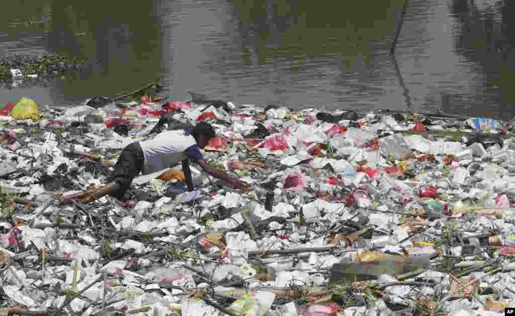 A scavenger collects plastic materials to sell at recycling plants on the river in Cikarang, West Java, Indonesia.