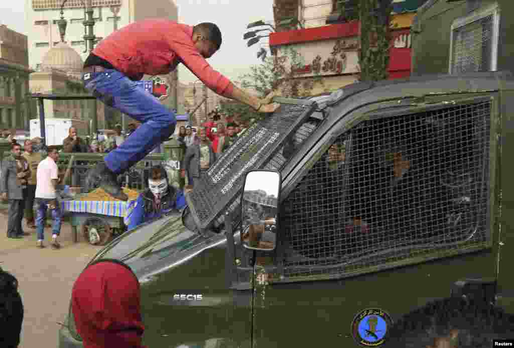 A protester jumps on a police vehicle as it passes by an anti-government protest in Cairo, Egypt.