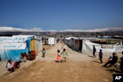 FILE - Refugees from Syria are seen outside their tents, in the town of Saadnayel, east Lebanon, April 23, 2019.