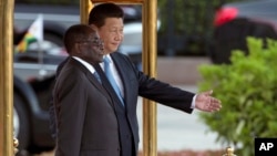 FILE - In this file photo taken on Aug. 25, 2014, Chinese President Xi Jinping, right, shows Zimbabwe's President Robert Mugabe the way during a welcome ceremony outside the Great Hall of the People in Beijing, China.