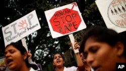 FILE - Indian physiotherapy students hold placards at a rally on the first anniversary of the fatal gang rape of a young woman in a bus New Delhi, India, Dec. 16, 2013.