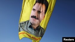 FILE - A banner with a picture of imprisoned Kurdish rebel leader Abdullah Ocalan is seen during a protest in Qamishli, Syria, Jan. 30, 2018.