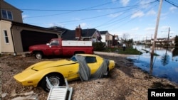 a Corvette and truck flooded by the storm surge of Superstorm Sandy stand in a driveway in Lindenhurst, New York. (Reuters)