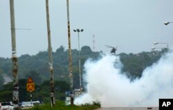 A helicopter fires teargas onto protestors during a demonstration over the hike in fuel prices in Harare, Zimbabwe, Tuesday, Jan. 15, 2019. A Zimbabwean military helicopter on Tuesday fired tear gas at demonstrators blocking a road and burning tyres.